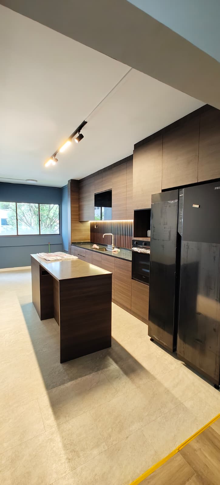 Kitchen portrait view with track lighting, dark timber island and full-height cabinetry